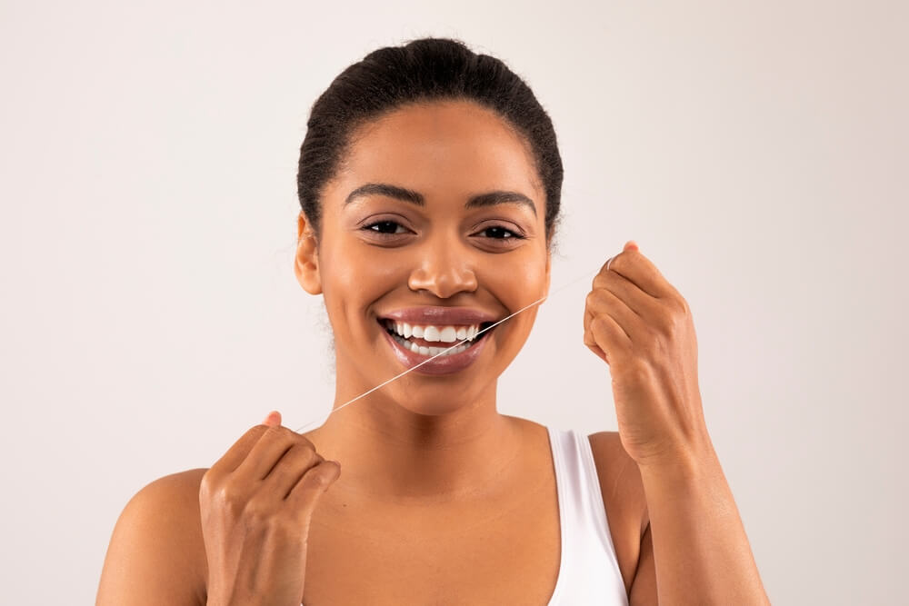 African American toothy female model flossing