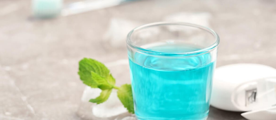 A glass full of mouthwash with flosser