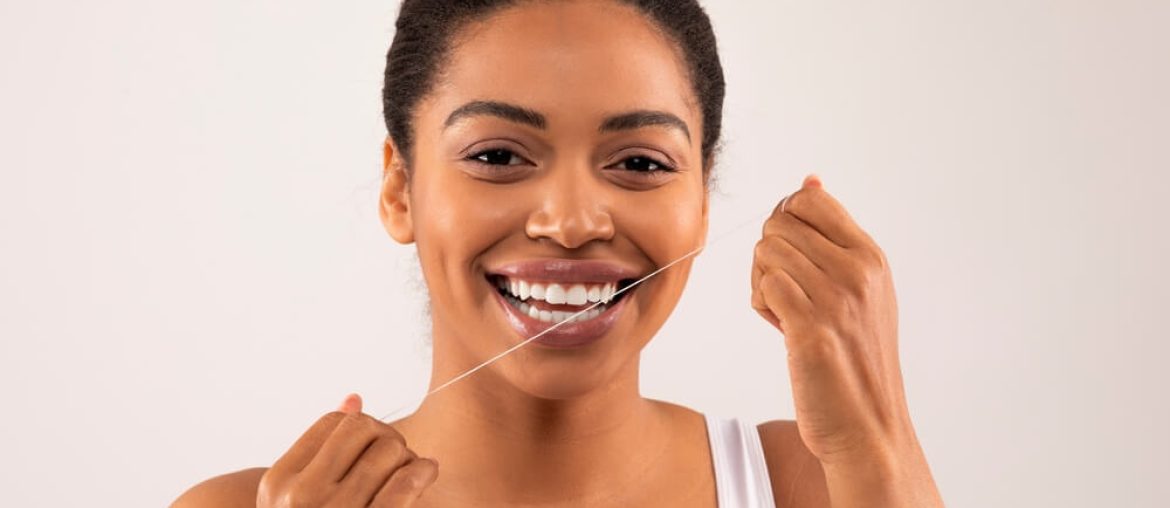African American toothy female model flossing